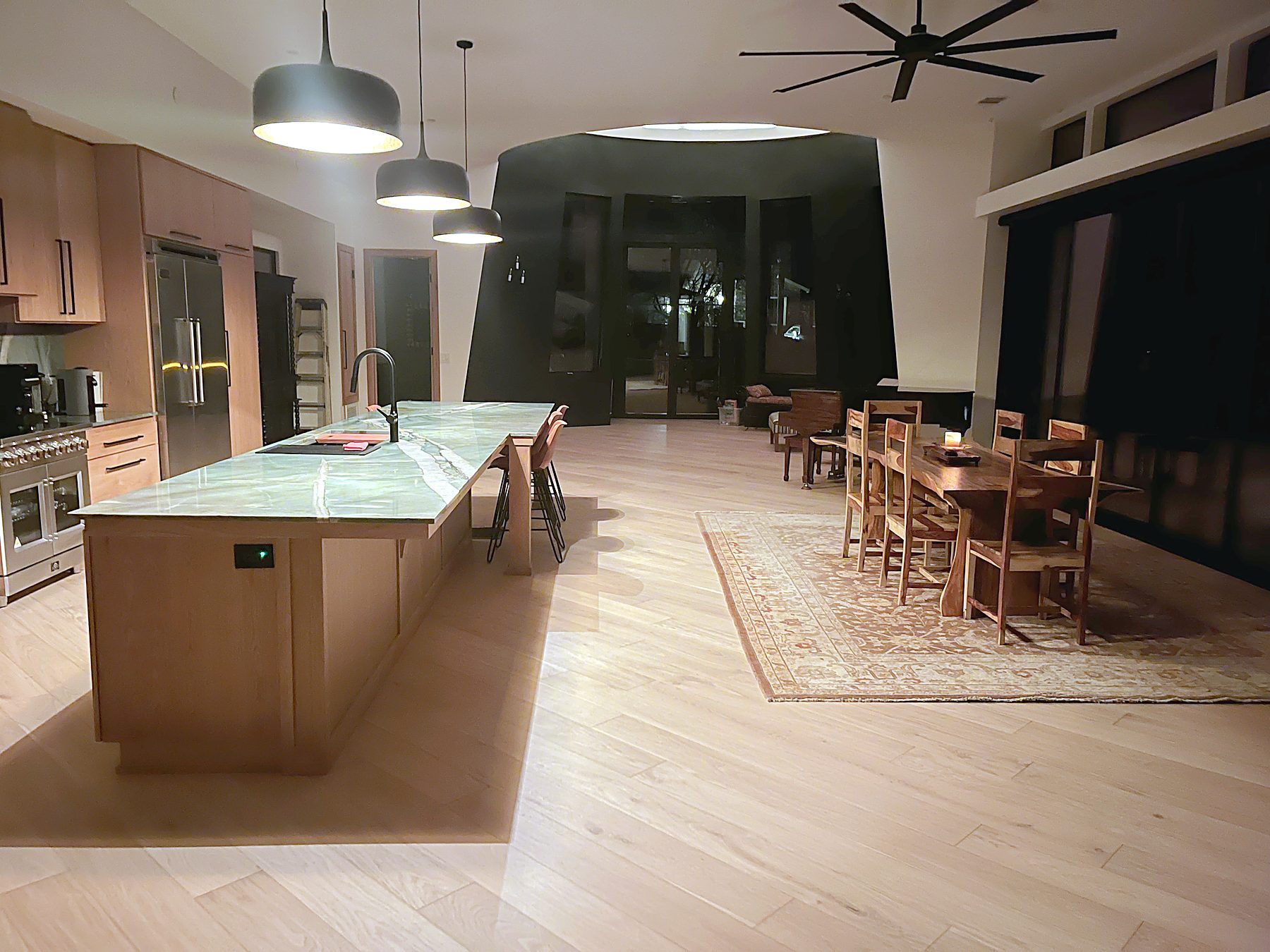 Finished open kitchen and great room with long stone-topped island and dining area