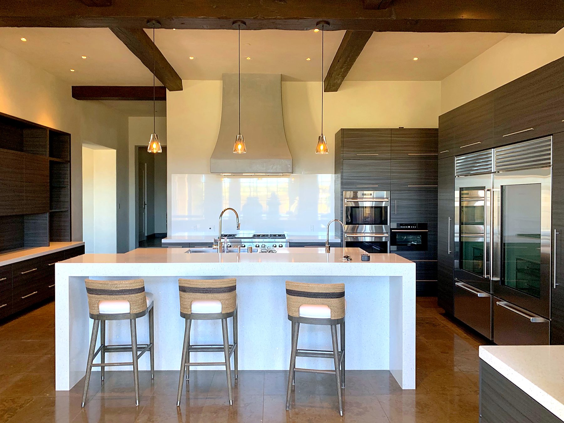 Finished kitchen with white waterfall island and exposed wood beams by Edgewood Remodel and Construction
