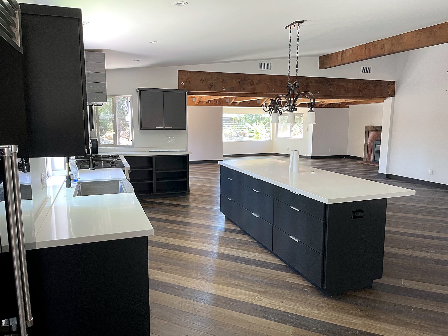 Open kitchen and great room with wood beams by Edgewood Remodel and Construction